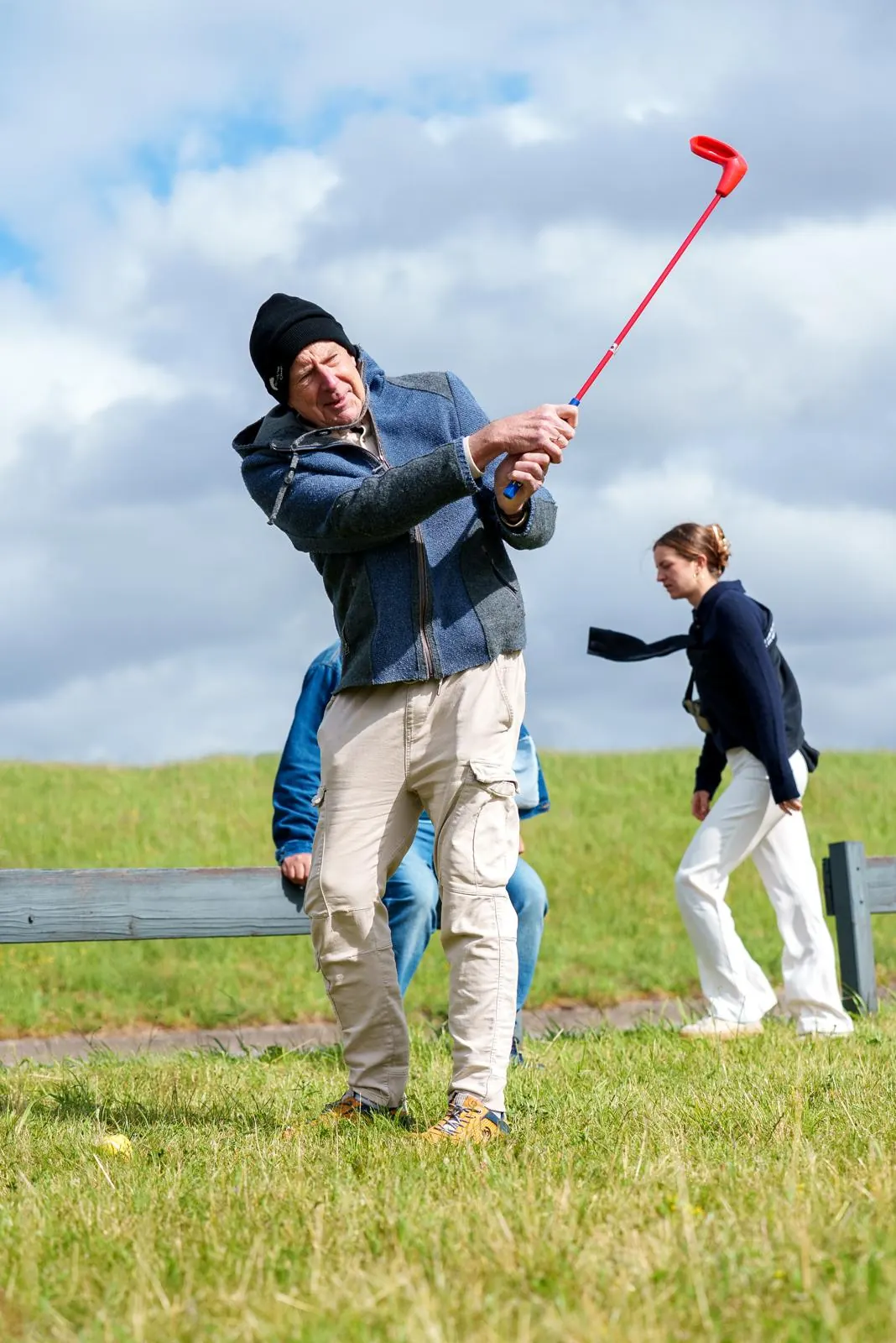 Golfschwung mit rotem Schläger auf der Deichwiese an der Dove-Elbe