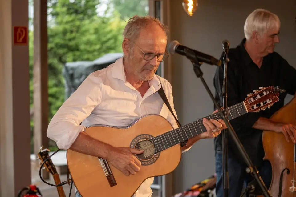Reinhold Beckmann spielt Gitarre in der Elb-Lodge, im Hintergrund ein Kontrabassist