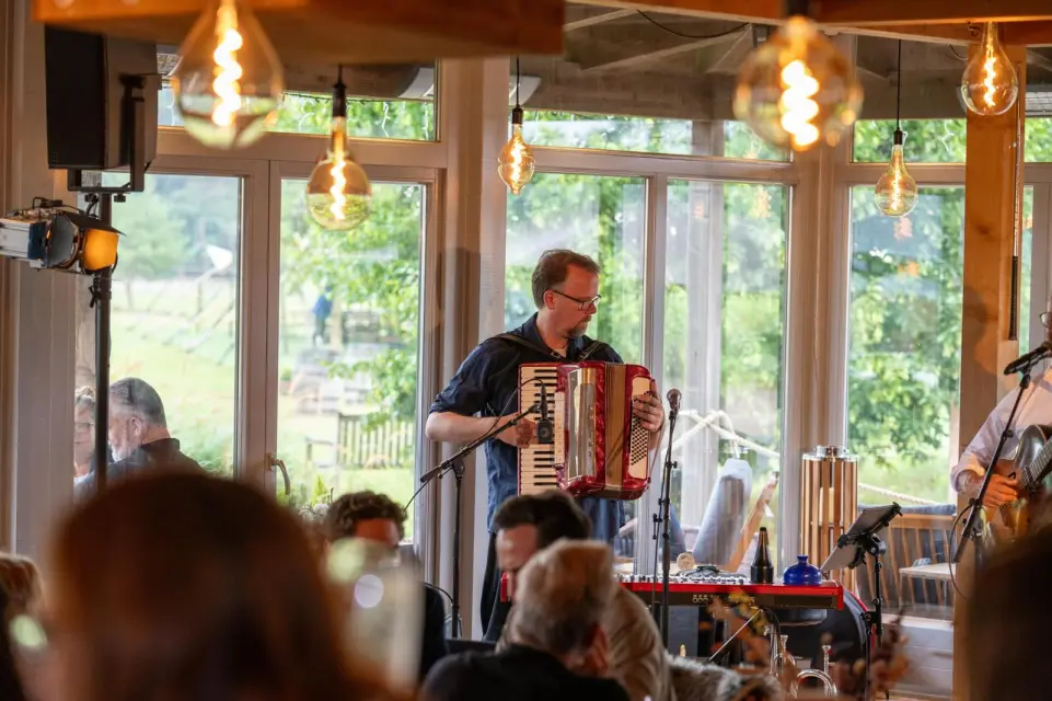 Musiker mit Akkordeon vor den Panoramafenstern der Elb-Lodge