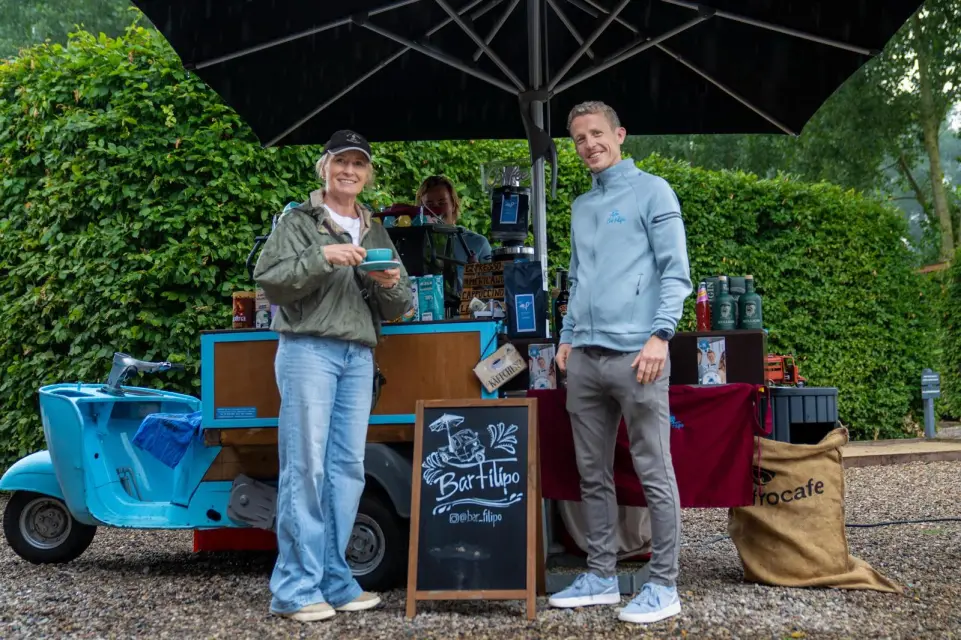 Gäste holen sich Kaffee am mobilen Kaffeewagen vor der Elb-Lodge