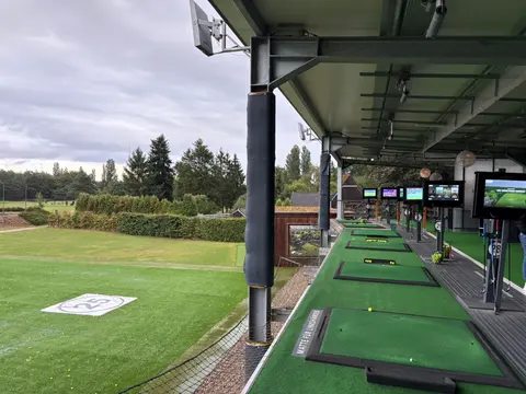 Covered tee boxes at the Golf Lounge driving range during the summer party despite rainy weather